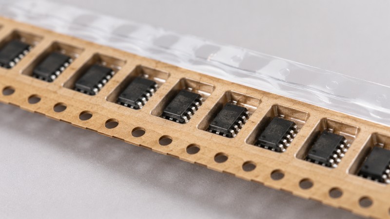 Paper carrier tape pockets showing correctly oriented electronic components before cover tape sealing